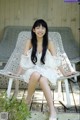 A woman in a white dress sitting on a white chair.