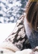 A woman laying in the snow wearing a sweater.