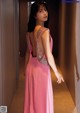 A woman in a pink dress standing in a hallway.